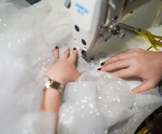 Mani che cuciono il tulle alla macchina da cucire