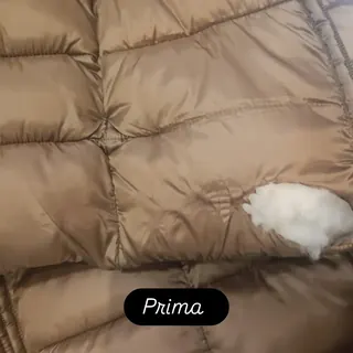 Piumino beige con una bruciatura sulla trapuntatura, prima della riparazione