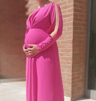 Donna in dolce attesa con abito lungo in crêpe fucsia