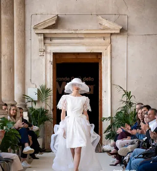 Modella in abito bianco corto con cappello in passerella